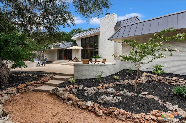 9 Mission Trce, New Braunfels, TX 78130 - rear view of property featuring a standing seam roof, a patio, a chimney, a metal roof, and brick siding