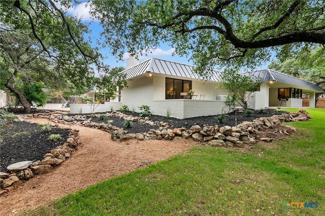 9 Mission Trce, New Braunfels, TX 78130 - view of side of home with brick siding, a standing seam roof, a metal roof, a chimney, and a yard