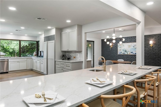 9 Mission Trce, New Braunfels, TX 78130 - kitchen featuring paneled refrigerator, dishwasher, light stone countertops, a breakfast bar area, and decorative backsplash