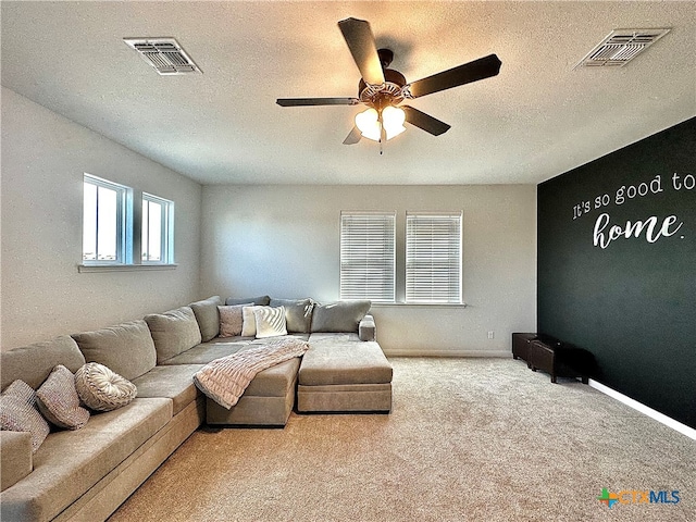 living room with a textured ceiling, light colored carpet, and ceiling fan