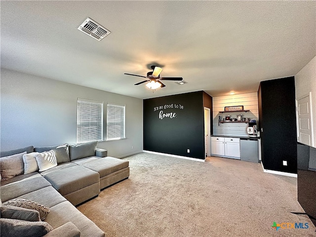 living room with a textured ceiling, light carpet, and ceiling fan