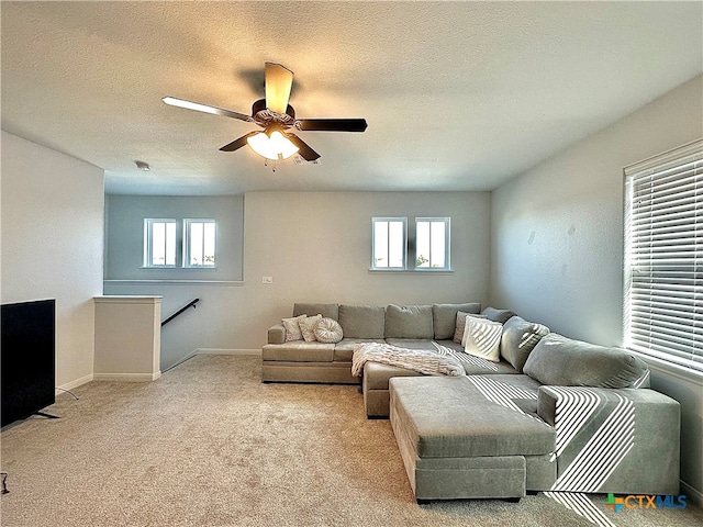 carpeted living room with a wealth of natural light, ceiling fan, and a textured ceiling