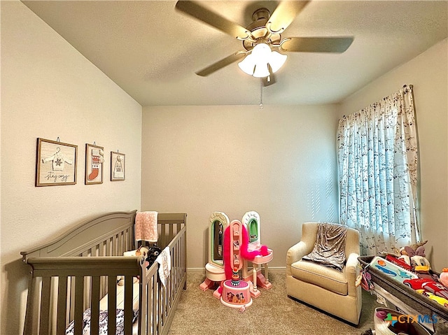 bedroom featuring a crib, carpet flooring, and ceiling fan