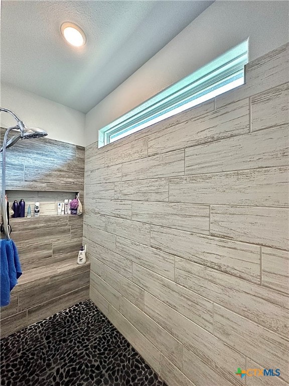 bathroom with a textured ceiling and tiled shower