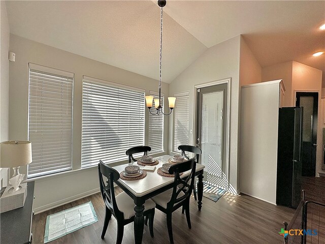 dining area featuring dark hardwood / wood-style floors, vaulted ceiling, and a notable chandelier