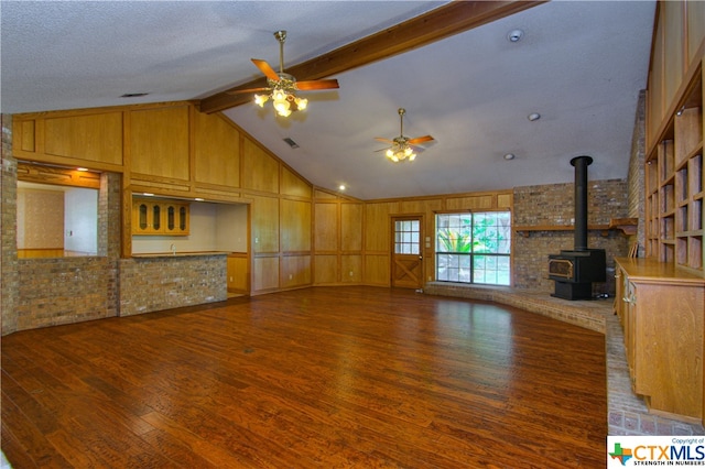 unfurnished living room with lofted ceiling with beams, a wood stove, a textured ceiling, dark hardwood / wood-style flooring, and ceiling fan