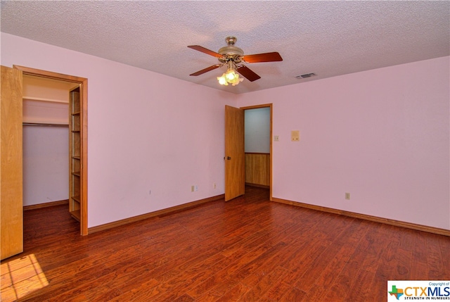 unfurnished bedroom with a walk in closet, hardwood / wood-style floors, and a textured ceiling