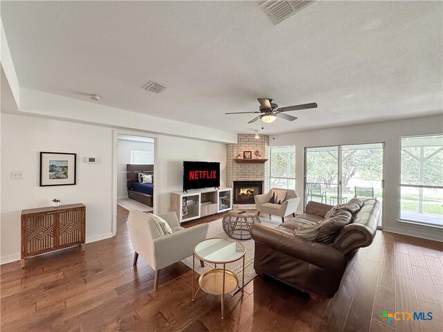 149 Gallagher Dr, Canyon Lake, TX 78133 - living room with wood-type flooring, ceiling fan, a brick fireplace, plenty of natural light, and a textured ceiling