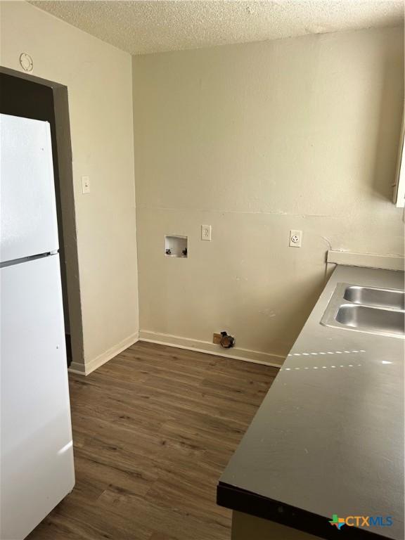 laundry room featuring sink, dark hardwood / wood-style flooring, a textured ceiling, and hookup for a washing machine