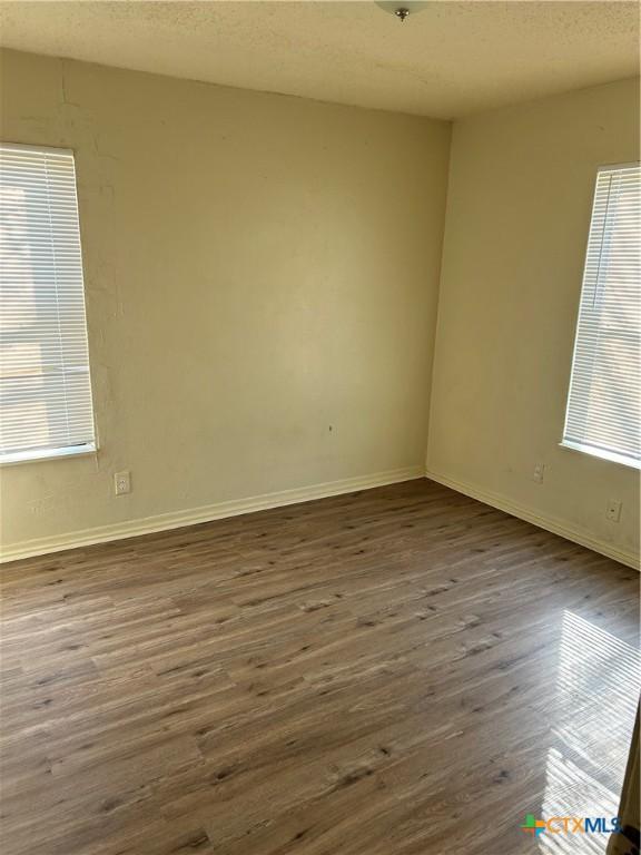 empty room featuring dark hardwood / wood-style floors and a textured ceiling