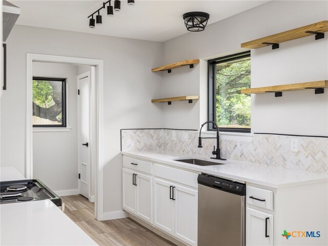 kitchen with open shelves, stainless steel dishwasher, a sink, tasteful backsplash, and light wood-style flooring