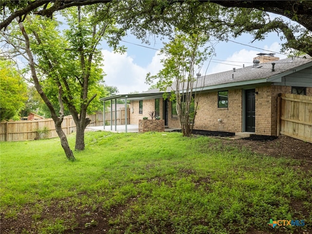 rear view of property featuring brick siding, a patio area, and a chimney