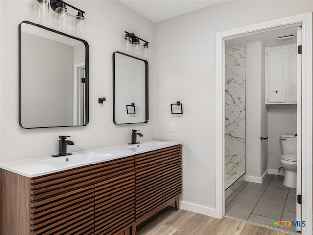 full bath with baseboards, toilet, double vanity, and wood finished floors