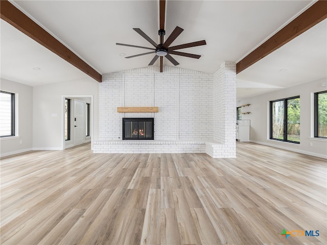unfurnished living room featuring ceiling fan, a brick fireplace, light wood-style flooring, brick wall, and baseboards