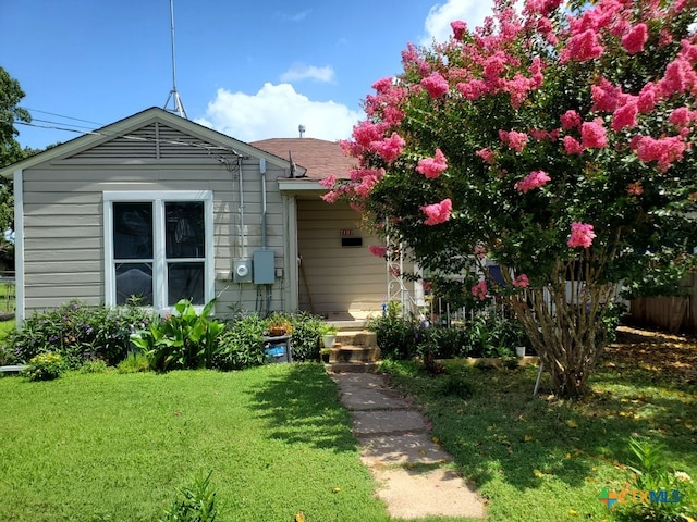 back of house with a lawn and a shingled roof