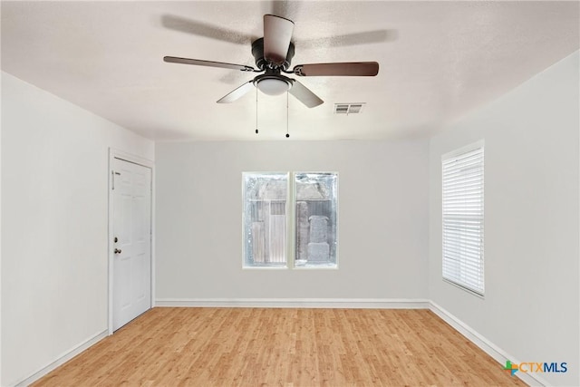 spare room with plenty of natural light, baseboards, visible vents, and light wood finished floors