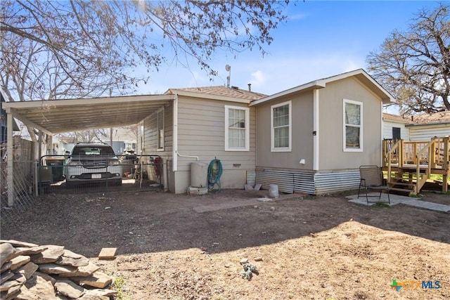 back of house featuring a carport, crawl space, driveway, and fence