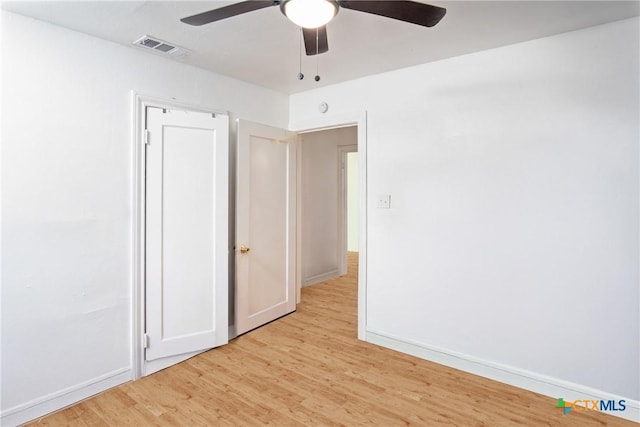 empty room with a ceiling fan, light wood-style floors, visible vents, and baseboards