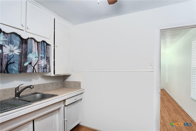 kitchen featuring light wood-style flooring, white cabinets, light countertops, and a sink