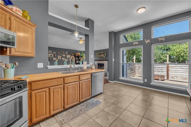 kitchen featuring sink, ceiling fan, decorative light fixtures, light tile patterned flooring, and stainless steel appliances