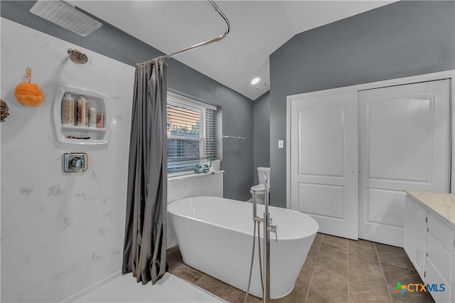 bathroom featuring a washtub, vanity, lofted ceiling, and tile patterned flooring