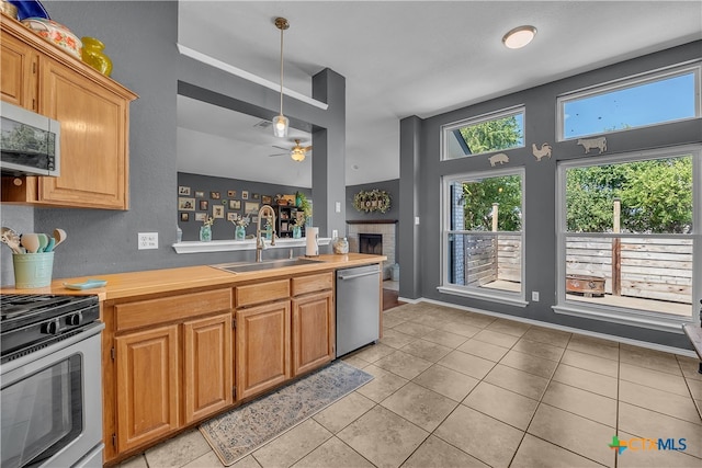 kitchen featuring stainless steel appliances, ceiling fan, sink, light tile patterned floors, and pendant lighting