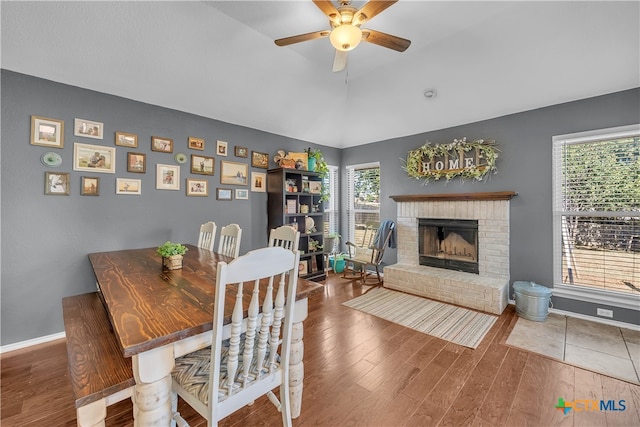 dining space featuring ceiling fan, a fireplace, plenty of natural light, and hardwood / wood-style flooring