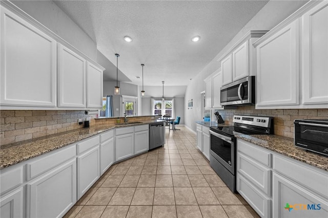 10103 Taylor Renee Dr, Killeen, TX 76542 - kitchen with appliances with stainless steel finishes, white cabinets, tasteful backsplash, a peninsula, and a textured ceiling