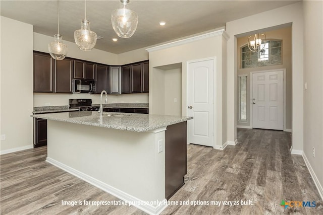 kitchen featuring a kitchen island with sink, black appliances, sink, hardwood / wood-style flooring, and light stone counters