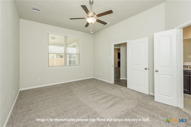 unfurnished bedroom with ceiling fan, ensuite bathroom, and light carpet