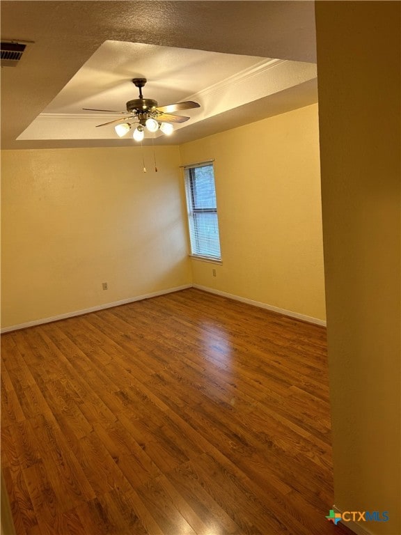 spare room with hardwood / wood-style floors, ceiling fan, a textured ceiling, and a raised ceiling