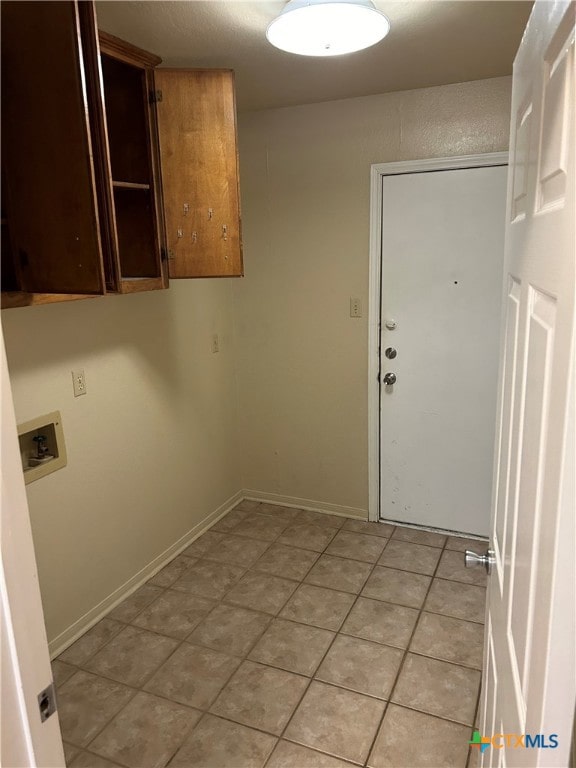 washroom with hookup for a washing machine, cabinets, and light tile patterned flooring