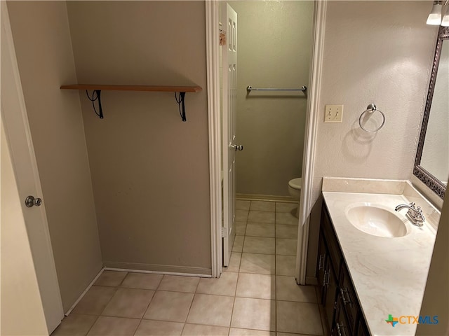 bathroom with toilet, vanity, and tile patterned flooring