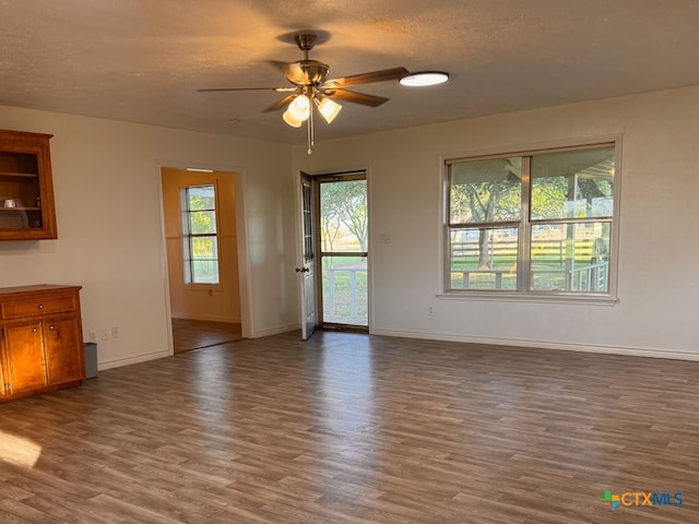 548 County Road 303, Shiner, TX 77984 - unfurnished living room featuring wood finished floors, healthy amount of natural light, ceiling fan, and a textured ceiling