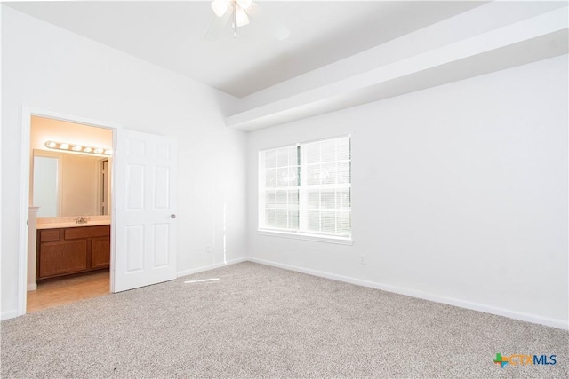 unfurnished bedroom with baseboards, a sink, connected bathroom, and light colored carpet