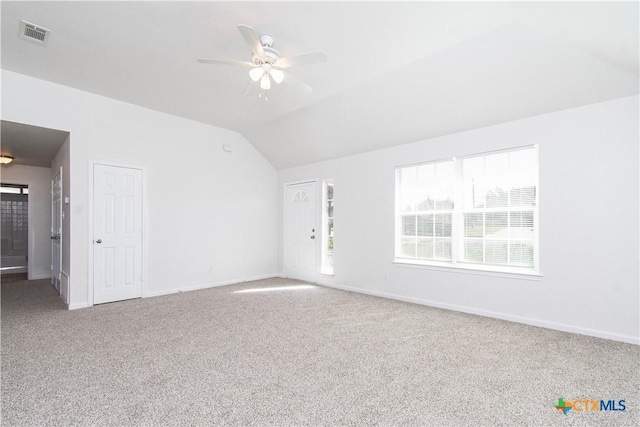 carpeted empty room featuring lofted ceiling, baseboards, visible vents, and a ceiling fan