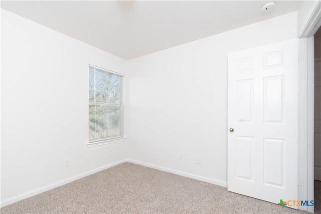 spare room featuring carpet floors and baseboards