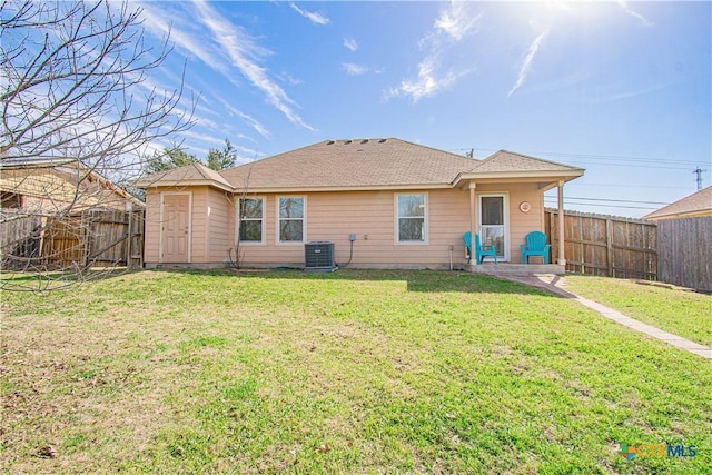 rear view of house featuring a fenced backyard, cooling unit, and a lawn