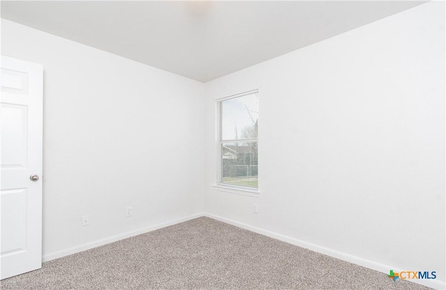 carpeted empty room featuring baseboards