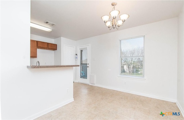 kitchen featuring brown cabinets, visible vents, a notable chandelier, and baseboards