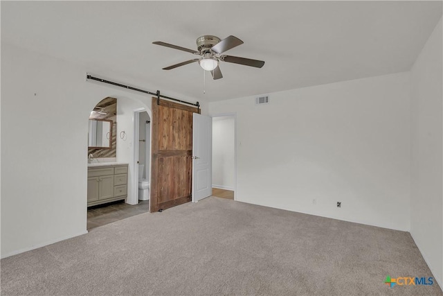 2002 Buckskin Trl, Temple, TX 76502 - unfurnished bedroom featuring a barn door, carpet floors, arched walkways, and ensuite bathroom