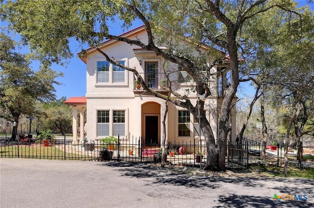 view of front of home with a fenced front yard, metal roof, and stucco siding