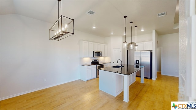 kitchen with white cabinetry, light wood-type flooring, stainless steel appliances, and an island with sink