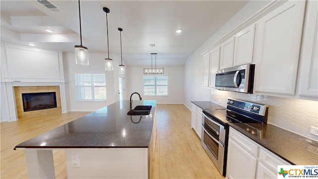 kitchen with white cabinetry, pendant lighting, stainless steel appliances, and light hardwood / wood-style flooring