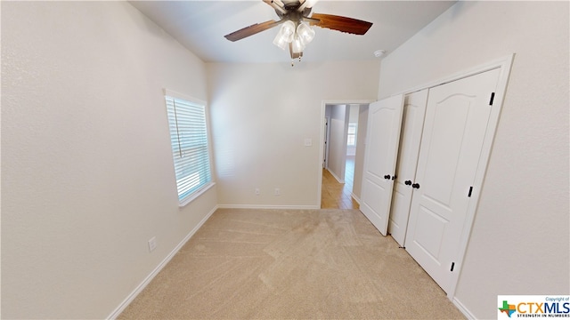 unfurnished bedroom featuring ceiling fan, light colored carpet, and a closet