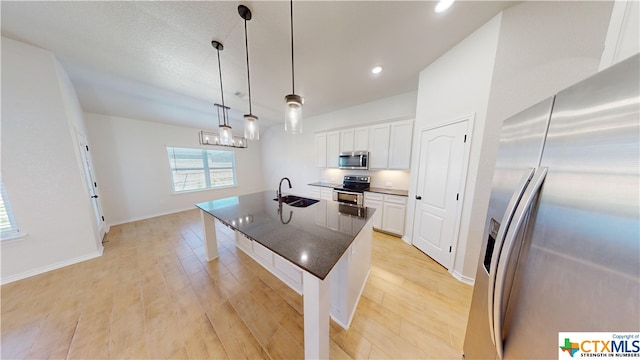 kitchen with sink, hanging light fixtures, light hardwood / wood-style floors, white cabinets, and appliances with stainless steel finishes