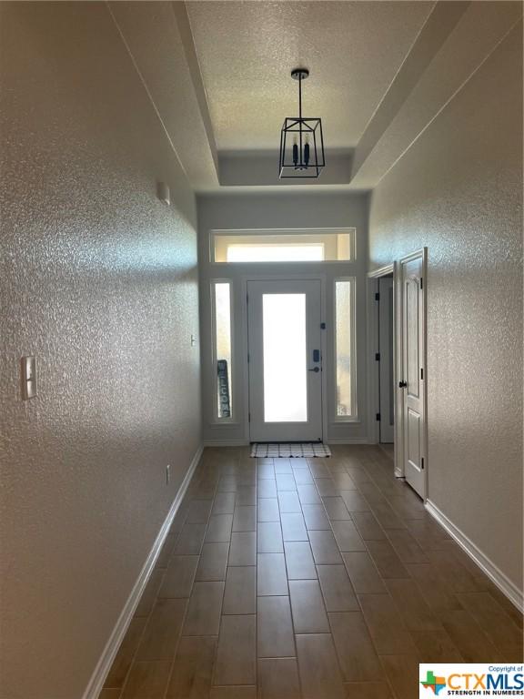 foyer featuring a raised ceiling and an inviting chandelier