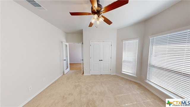 unfurnished bedroom featuring light carpet, a closet, and ceiling fan