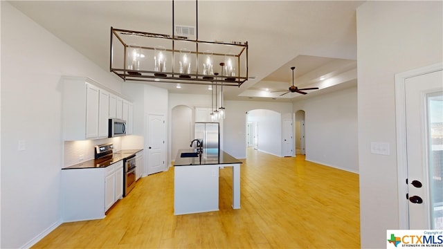 kitchen featuring stainless steel appliances, ceiling fan, pendant lighting, white cabinets, and light hardwood / wood-style floors