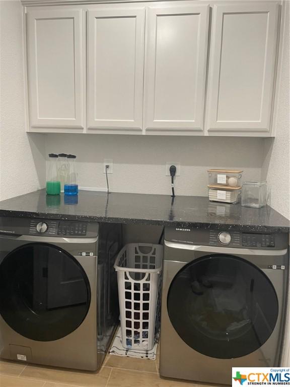 washroom featuring cabinets, light tile patterned floors, and separate washer and dryer